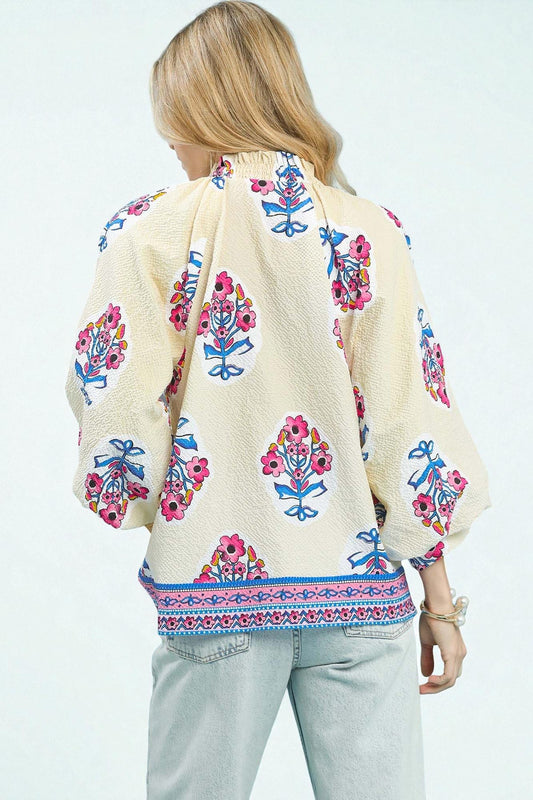 Person wearing a cream-colored shawl with colorful floral patterns on a white background