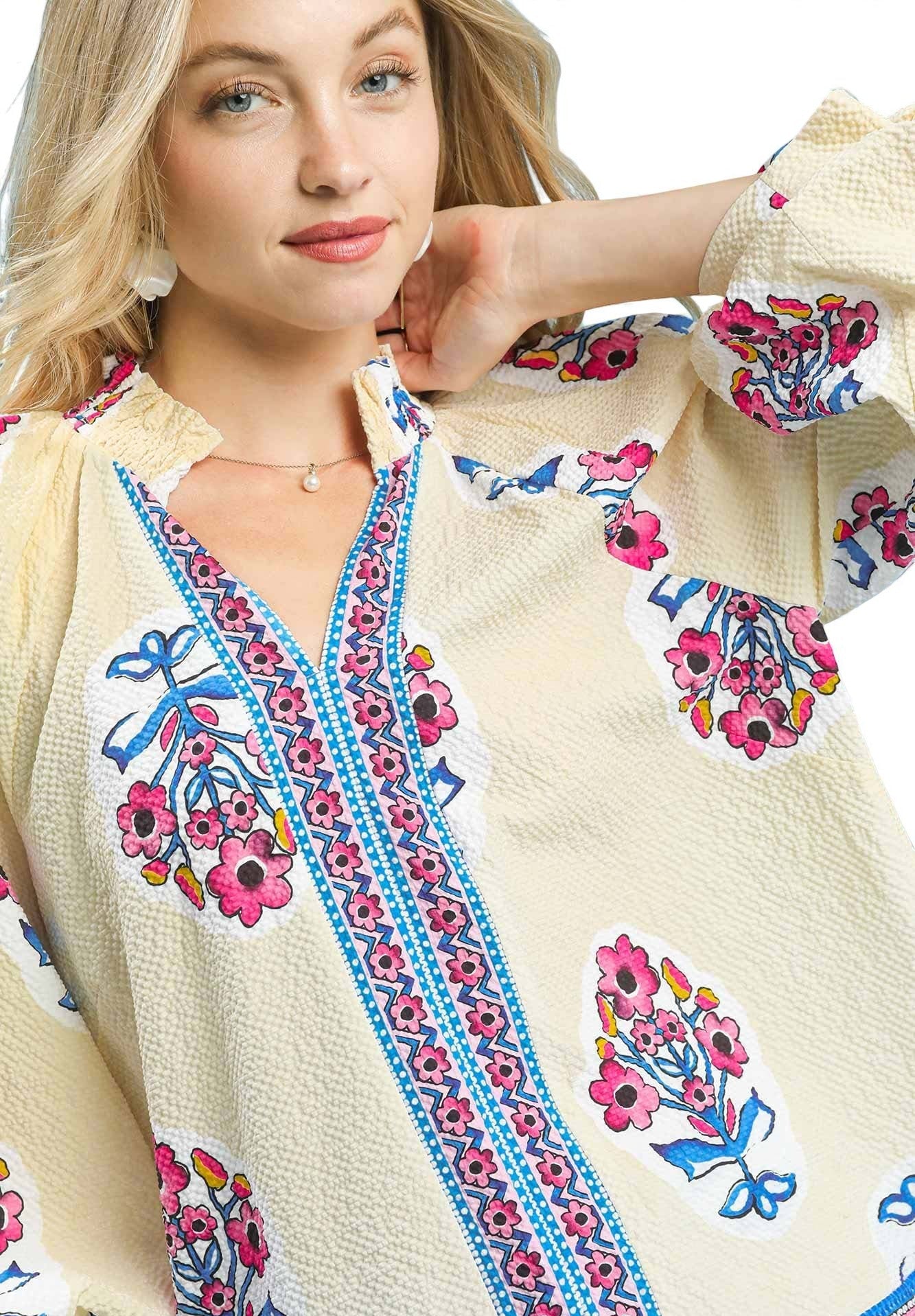 Woman wearing a cream-colored embroidered blouse with floral patterns on a white background