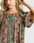 Woman wearing a colorful patterned blouse with a plain background