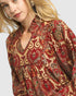 Woman wearing a patterned blouse with a neutral background