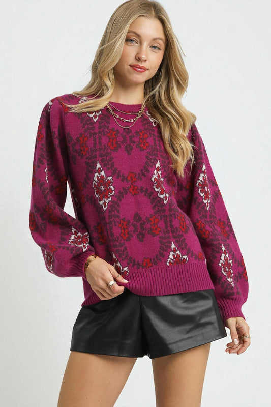 Woman wearing a patterned magenta sweater and black leather shorts on a white background