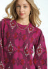 Woman wearing a pink patterned sweater with a white background