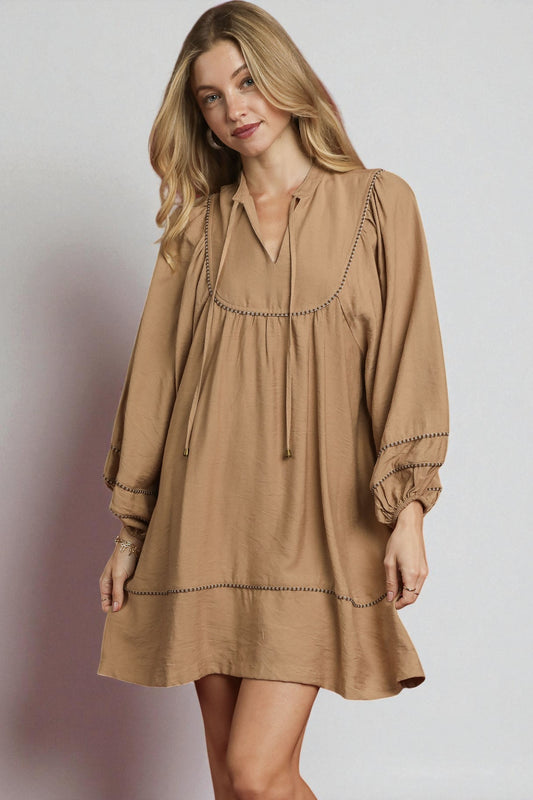 Woman wearing a brown dress with a plain background