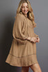 Woman wearing a beige dress against a gray background