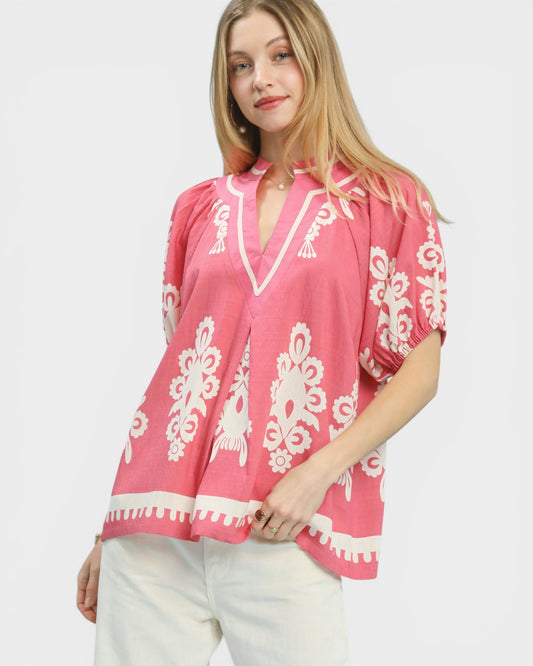 Woman wearing a pink blouse with white patterns on a white background