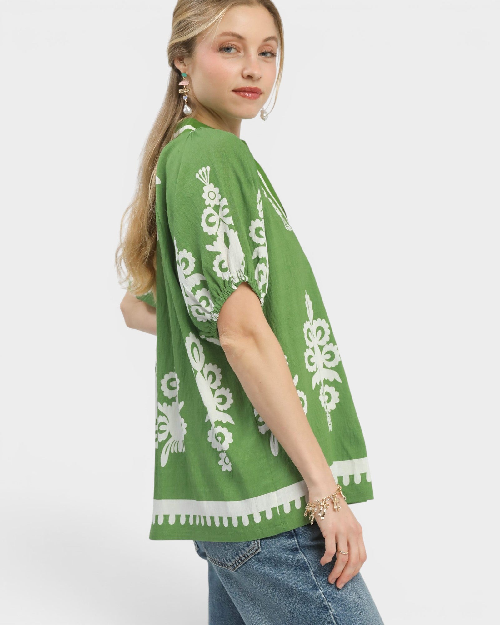 Woman wearing a green kimono-style top with white patterns on a white background
