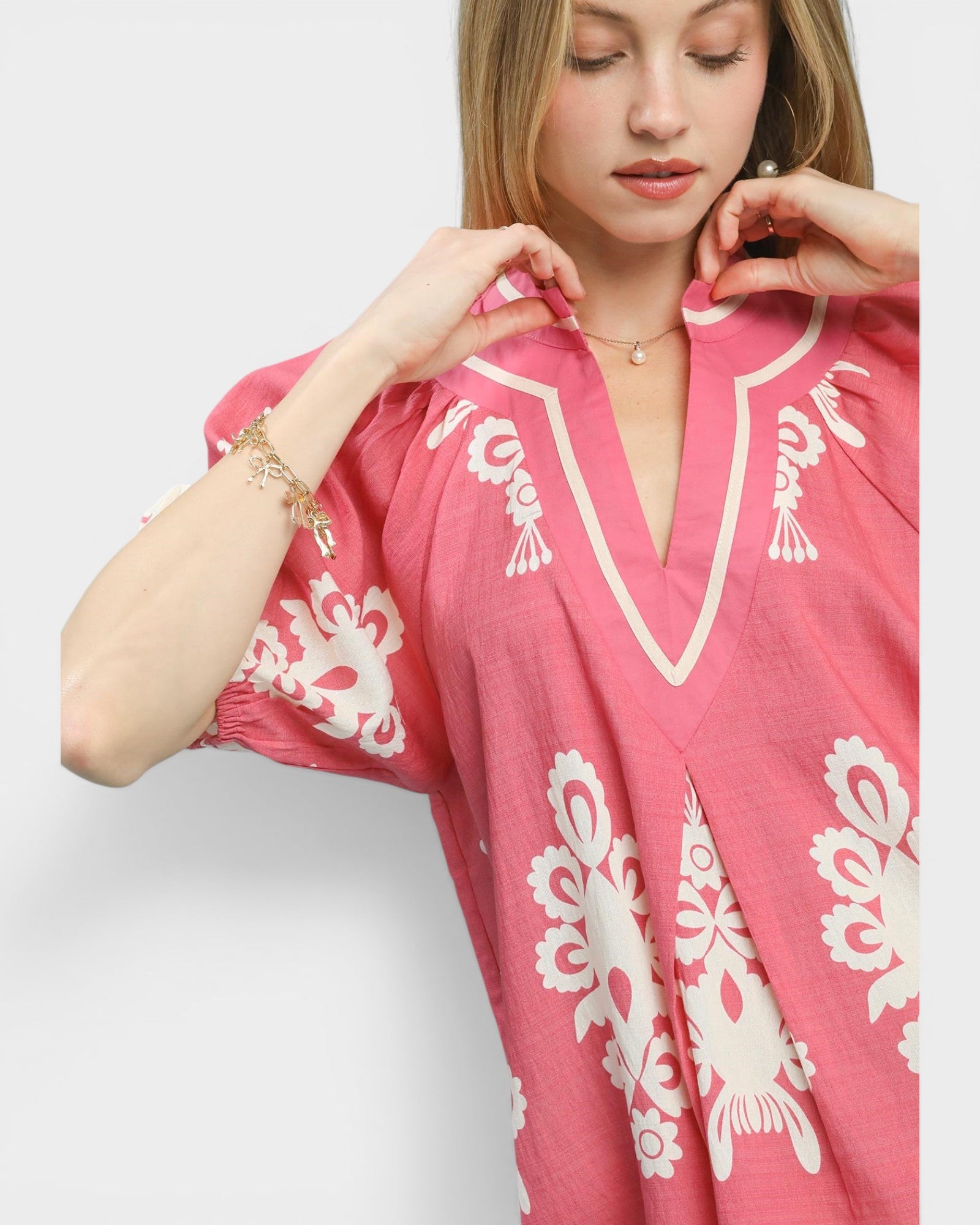 Woman wearing a pink dress with white lace patterns on a plain background