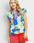 Woman wearing a colorful floral top and red shorts on a light gray background