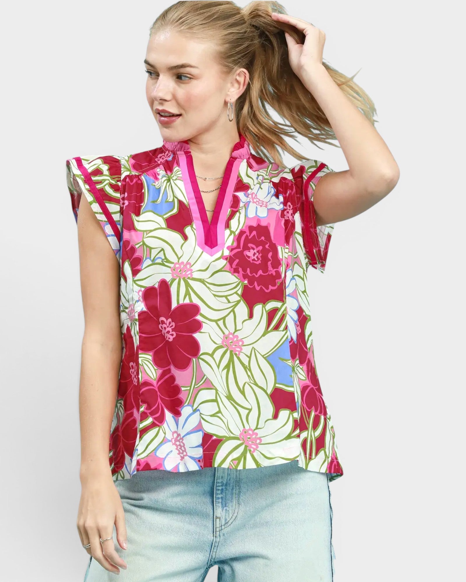 Woman wearing a colorful floral blouse against a plain background
