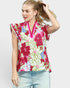 Woman wearing a colorful floral blouse against a plain background