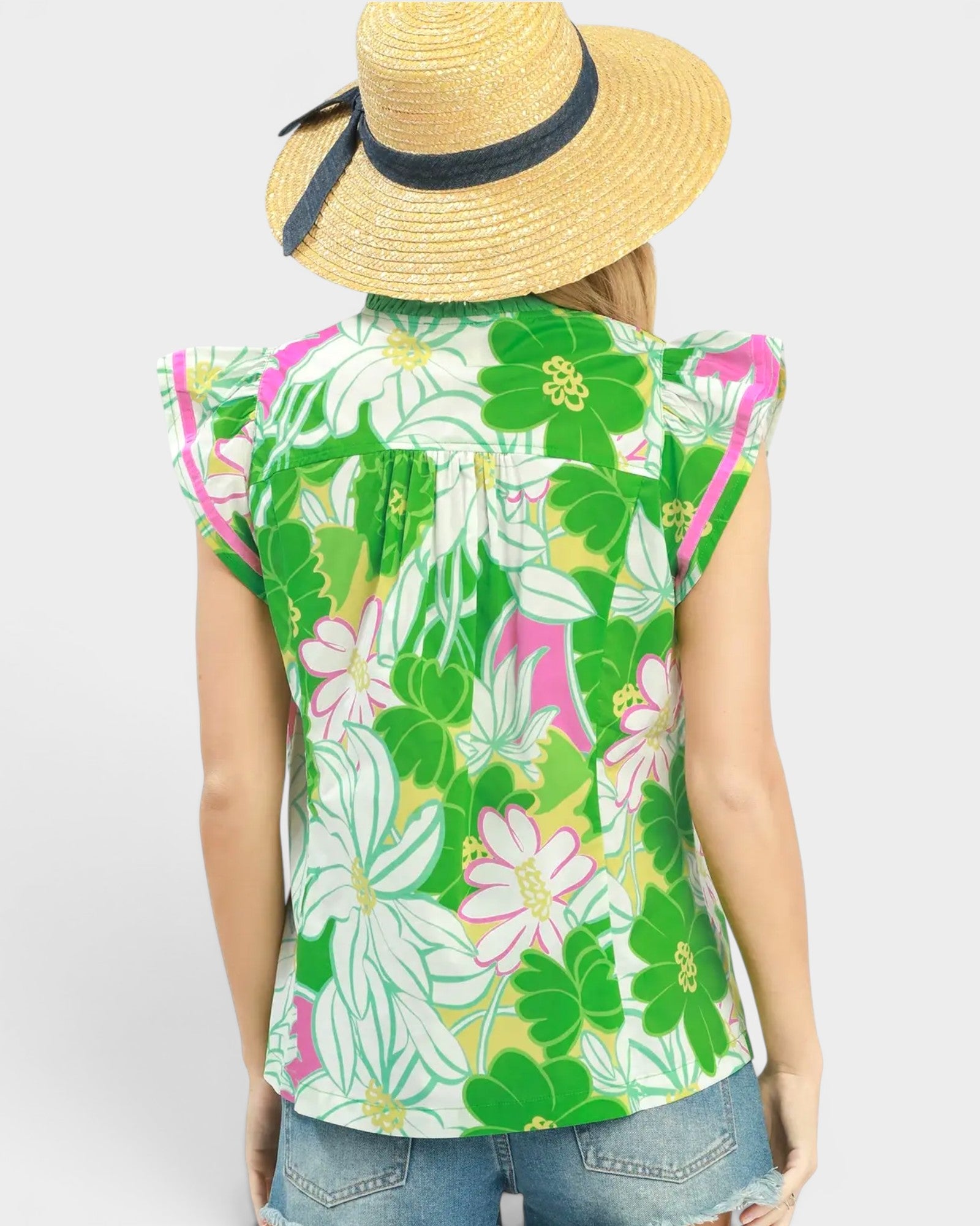 Person wearing a sleeveless floral top with a straw hat on a white background