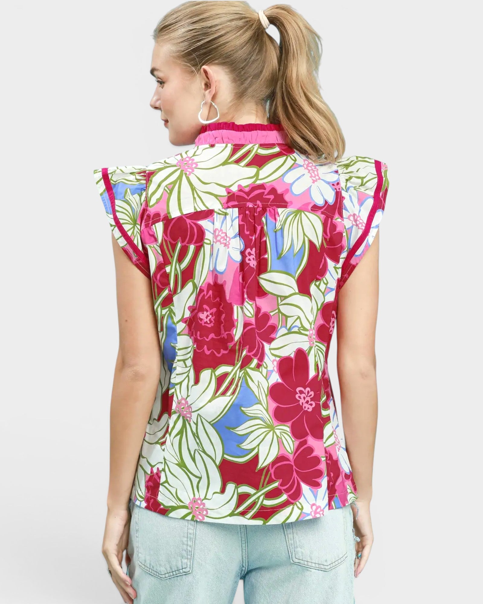 Woman wearing a colorful floral sleeveless blouse on a white background