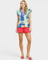 Woman wearing a colorful floral top and pink shorts on a white background