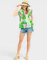 Woman wearing a colorful floral shirt and denim shorts on a white background