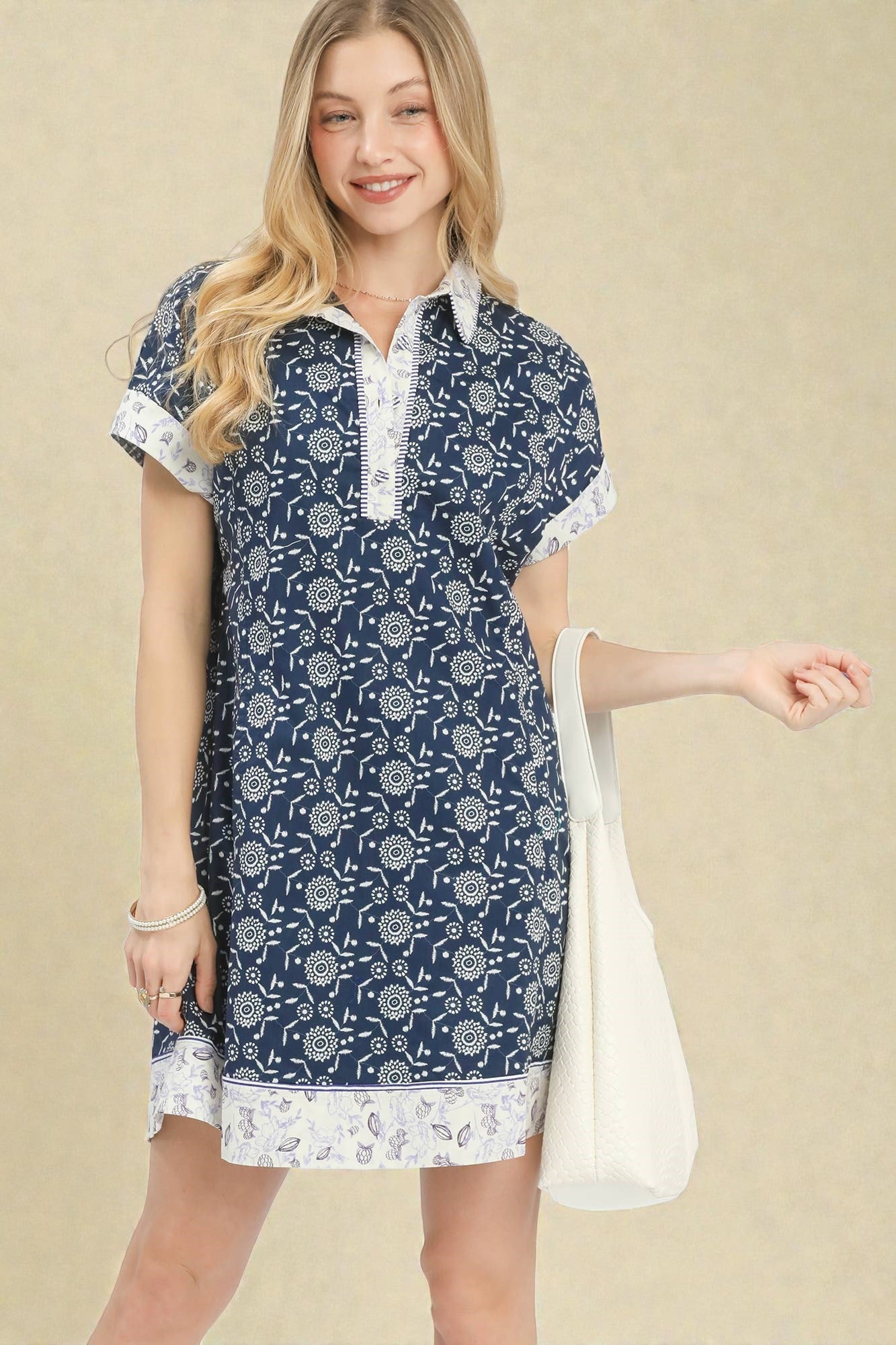 Woman wearing a blue patterned dress with white accents on a beige background