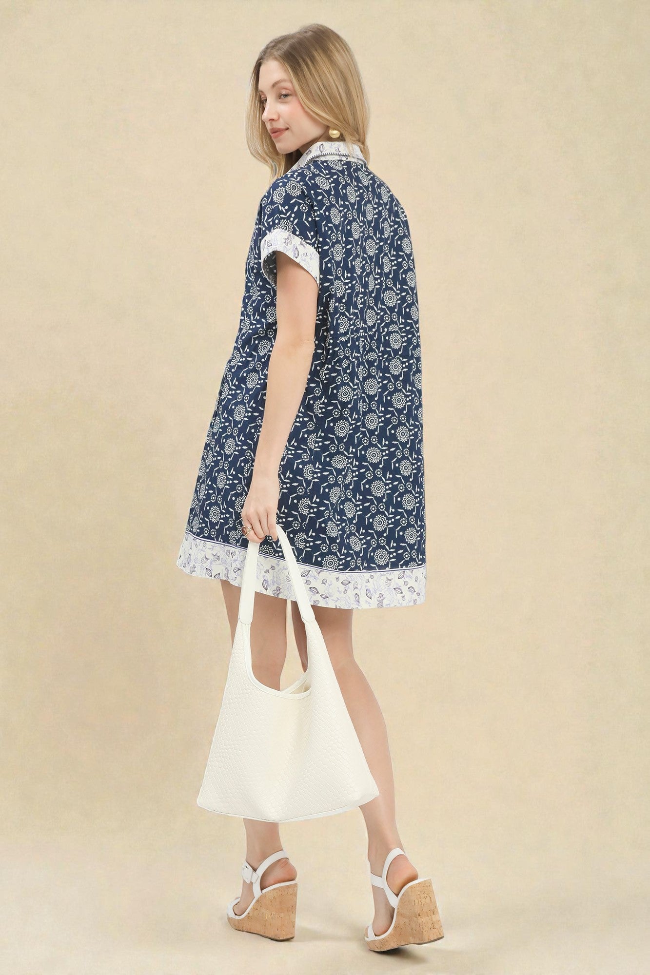 Woman wearing a blue floral dress with white accents on a beige background