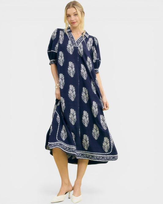 Woman wearing a navy blue dress with white floral patterns on a white background
