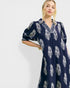 Woman wearing a navy dress with white floral patterns on a white background