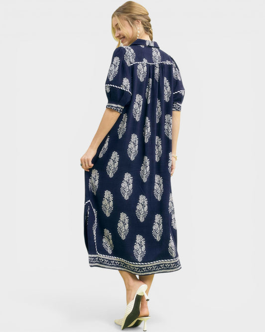 Woman wearing a navy dress with white floral pattern on a white background