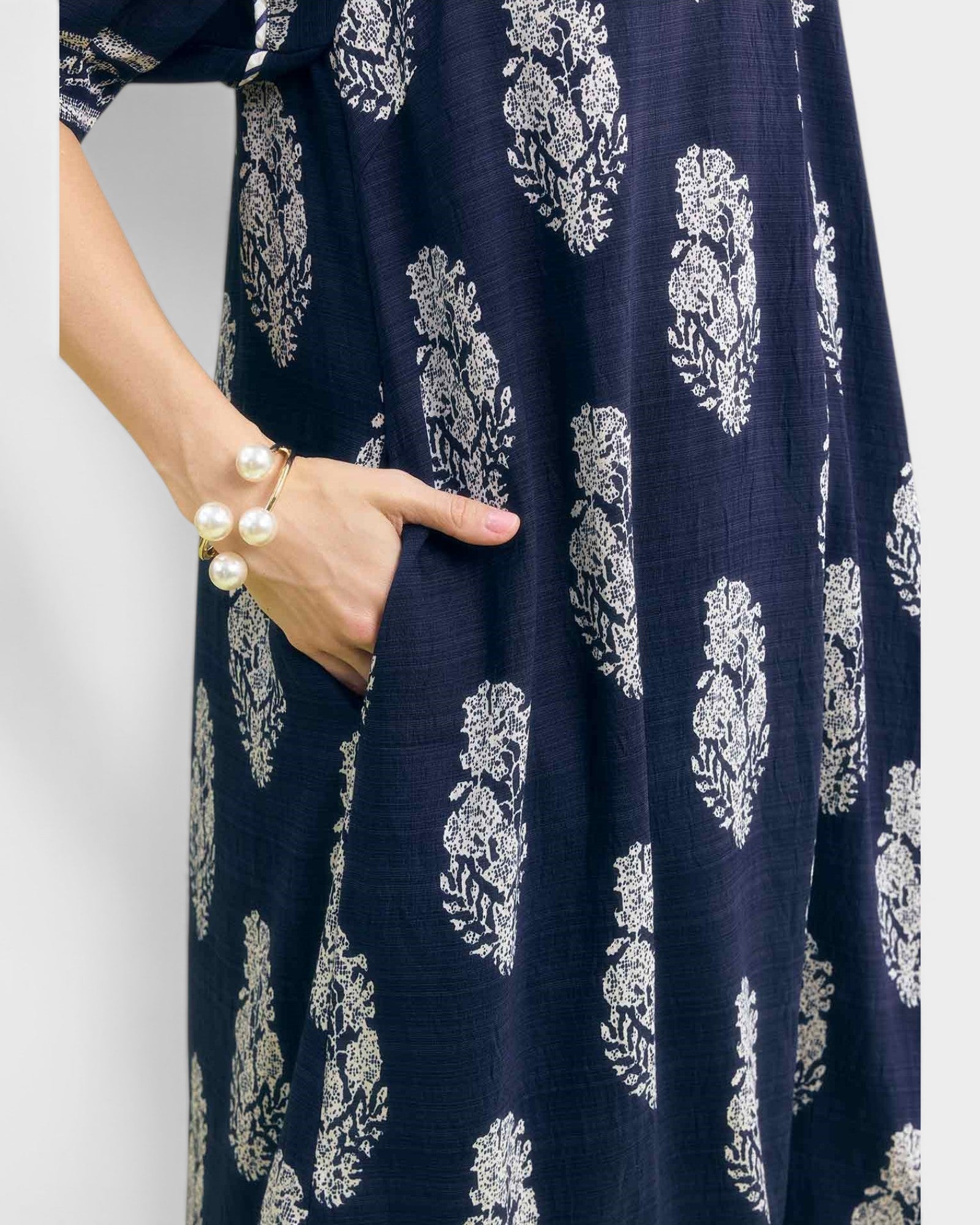 Navy blue dress with white floral pattern worn by a person on a plain background