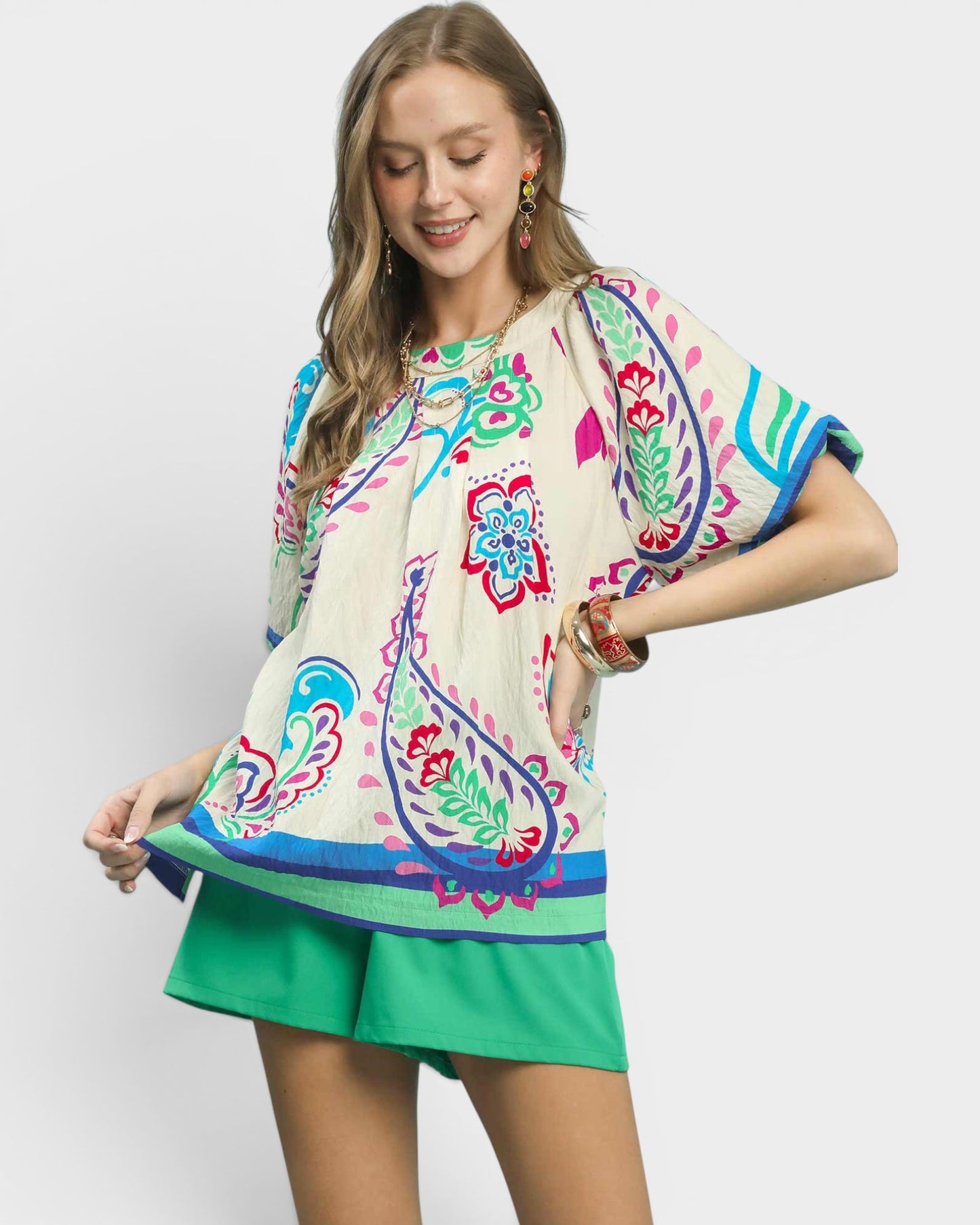 Woman wearing a colorful patterned top with a plain background