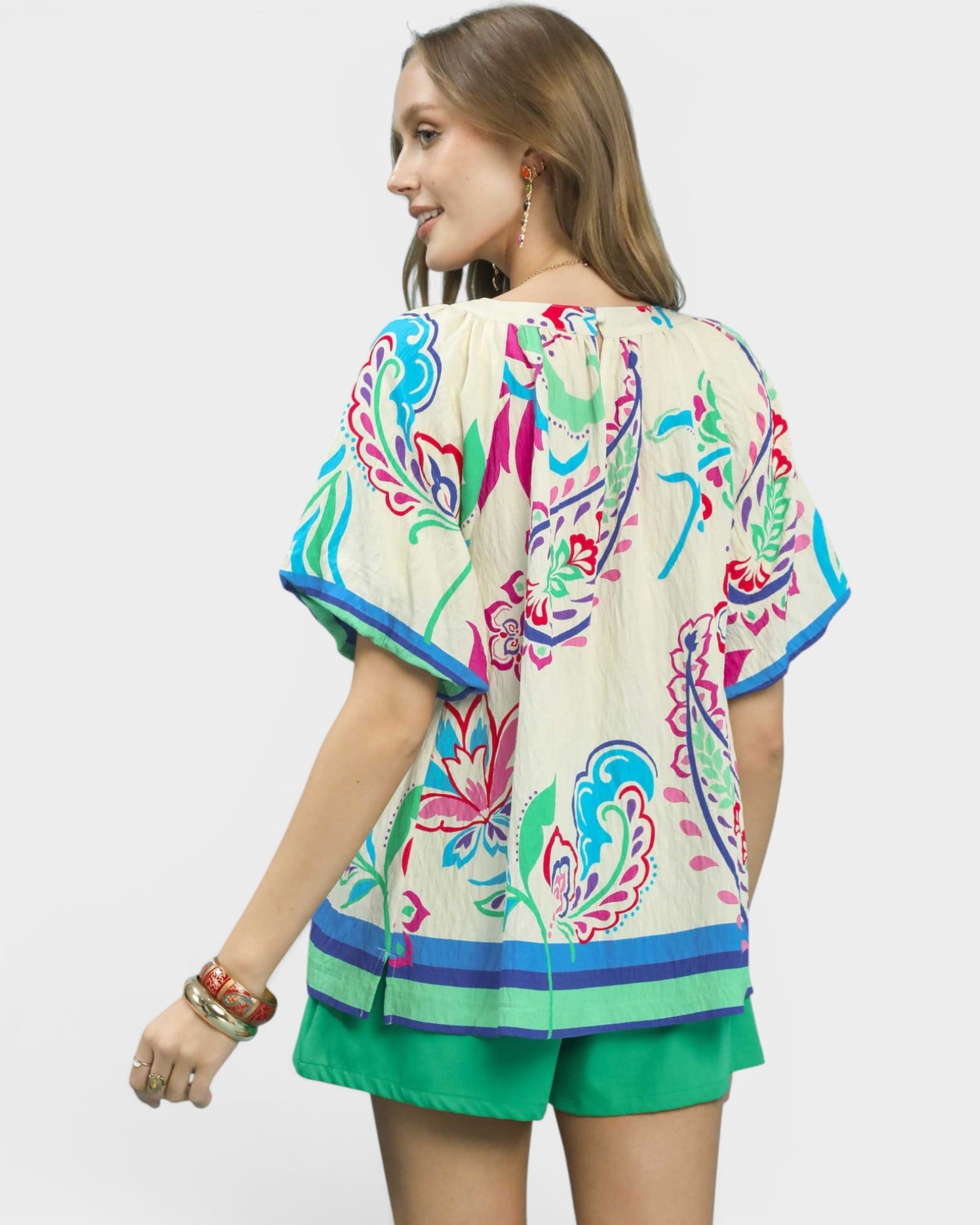 Woman wearing a colorful floral kimono-style top with green shorts on a white background