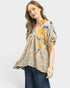 Woman wearing a patterned beige blouse with blue and yellow accents on a white background