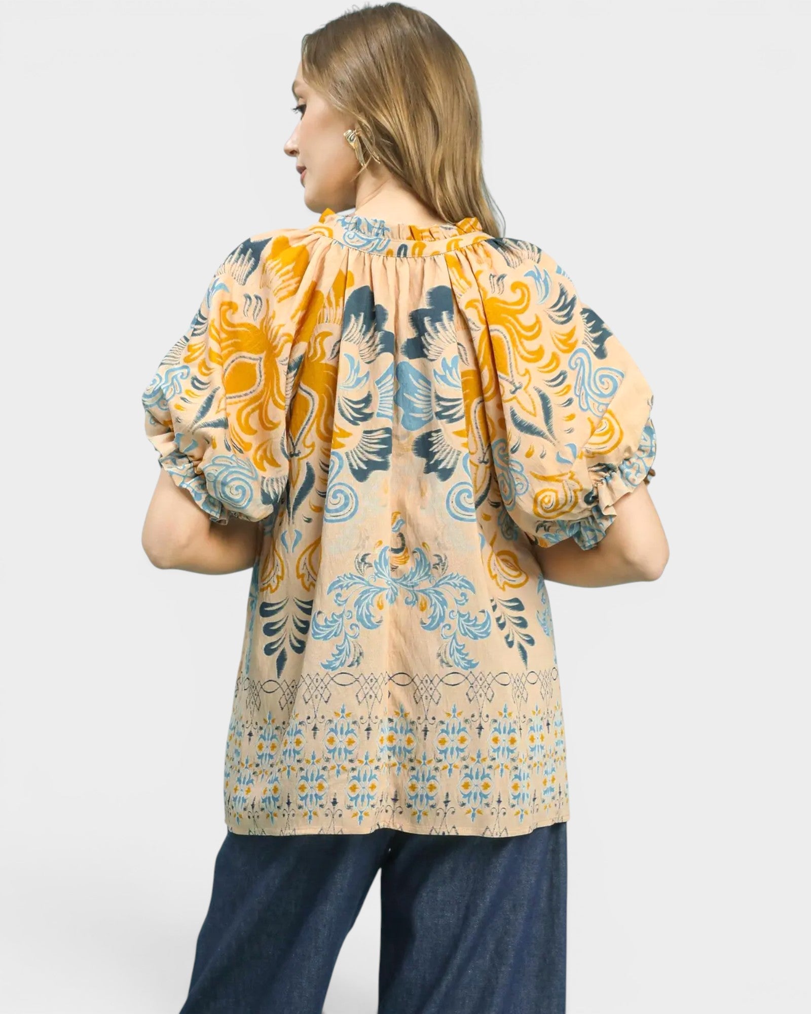 Woman wearing a patterned blouse with puff sleeves on a white background