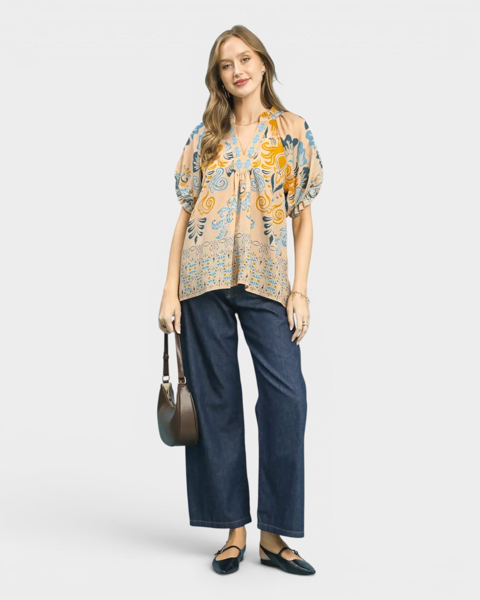 Woman wearing a patterned blouse and blue jeans on a white background