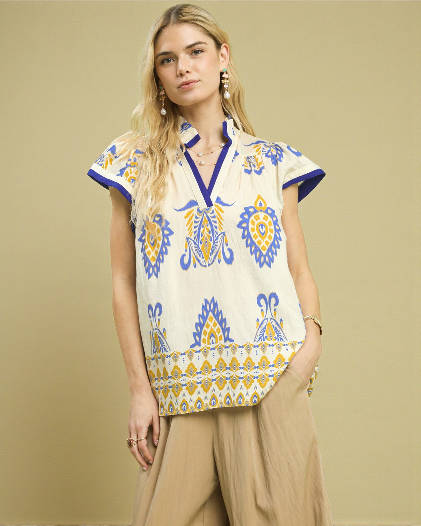Woman wearing a patterned top with a beige background
