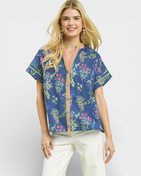 Woman wearing a blue floral patterned blouse with a pink zipper on a white background