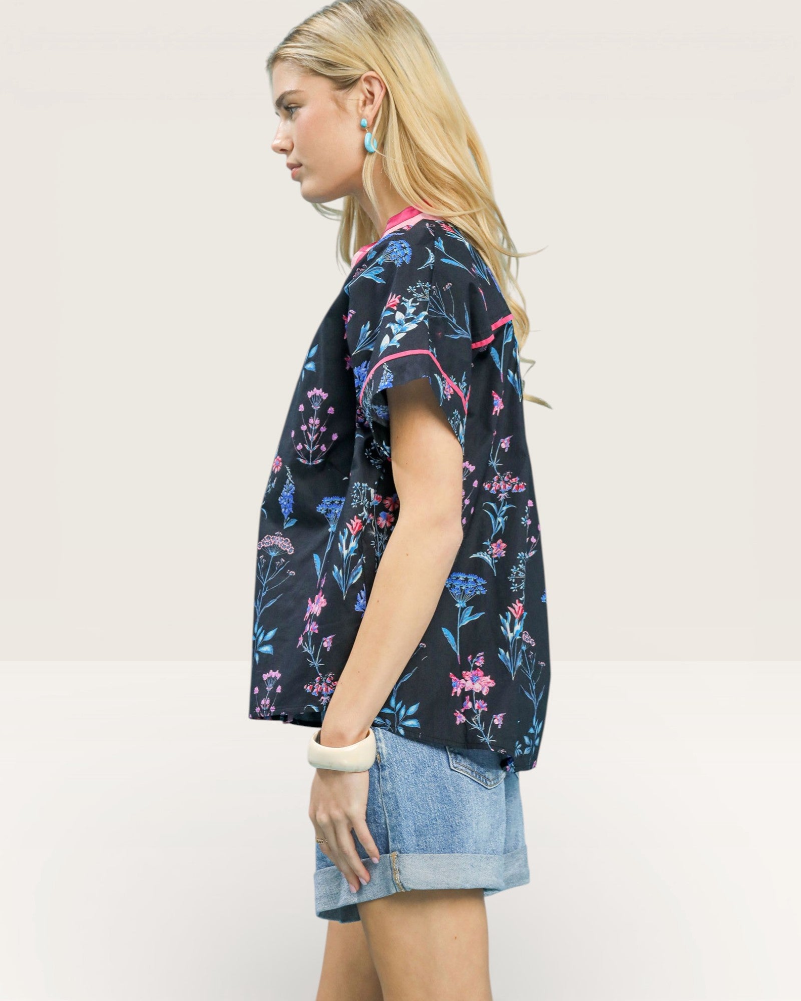 Woman wearing a dark floral patterned shirt with a plain background