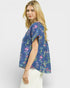 Woman wearing a blue floral patterned top against a white background