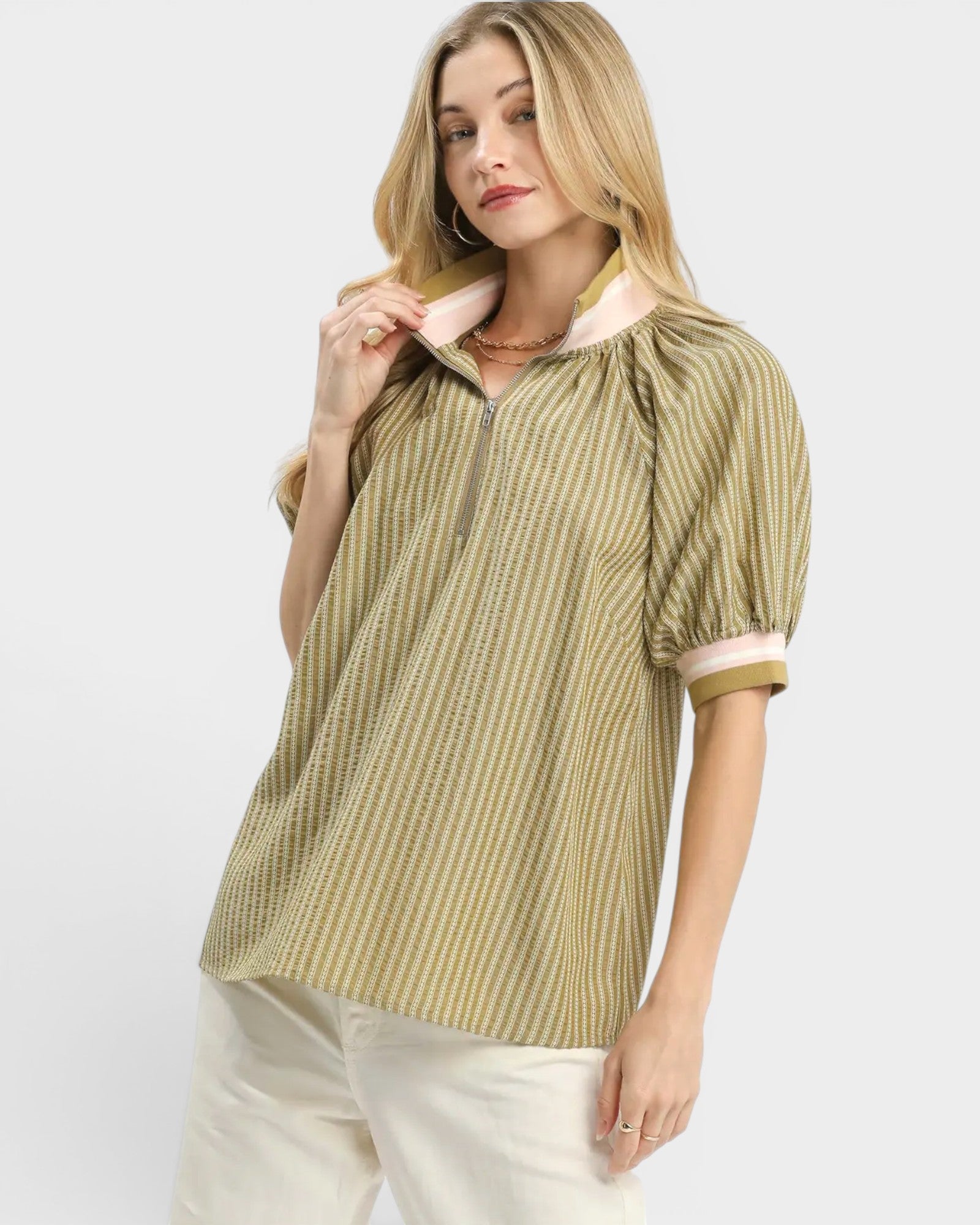 Woman wearing a green and white striped blouse with a plain background
