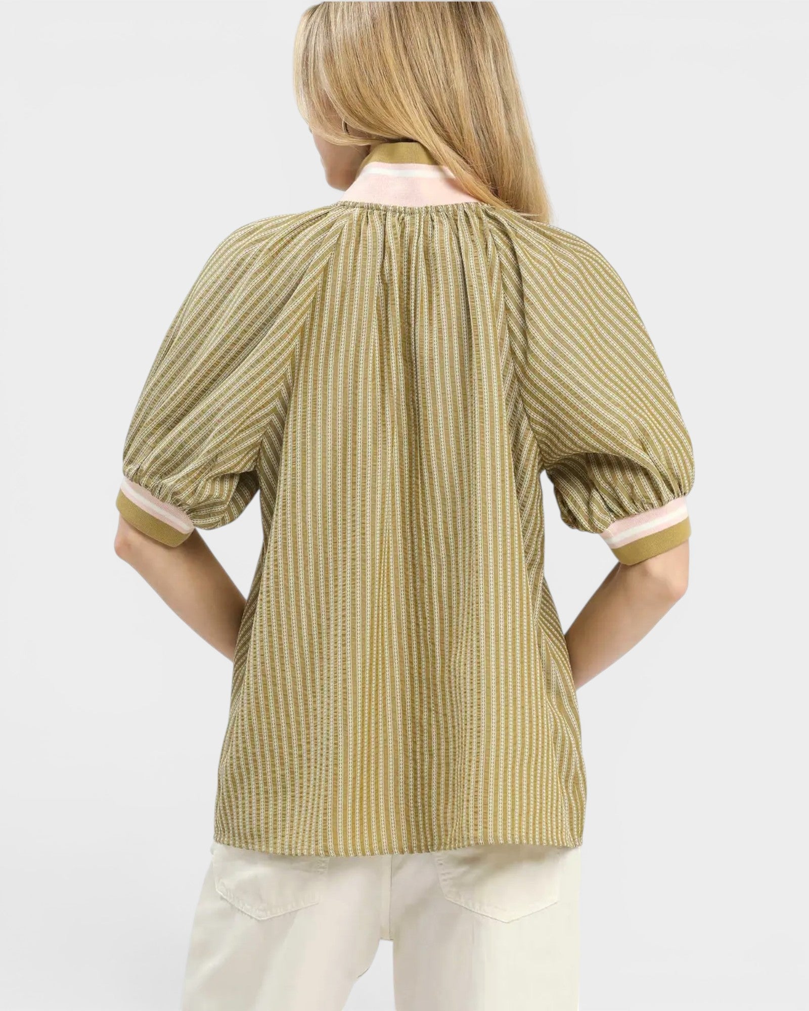 Woman wearing a green and white striped blouse with a plain background