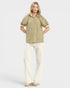 Woman wearing a striped blouse and white pants on a light background