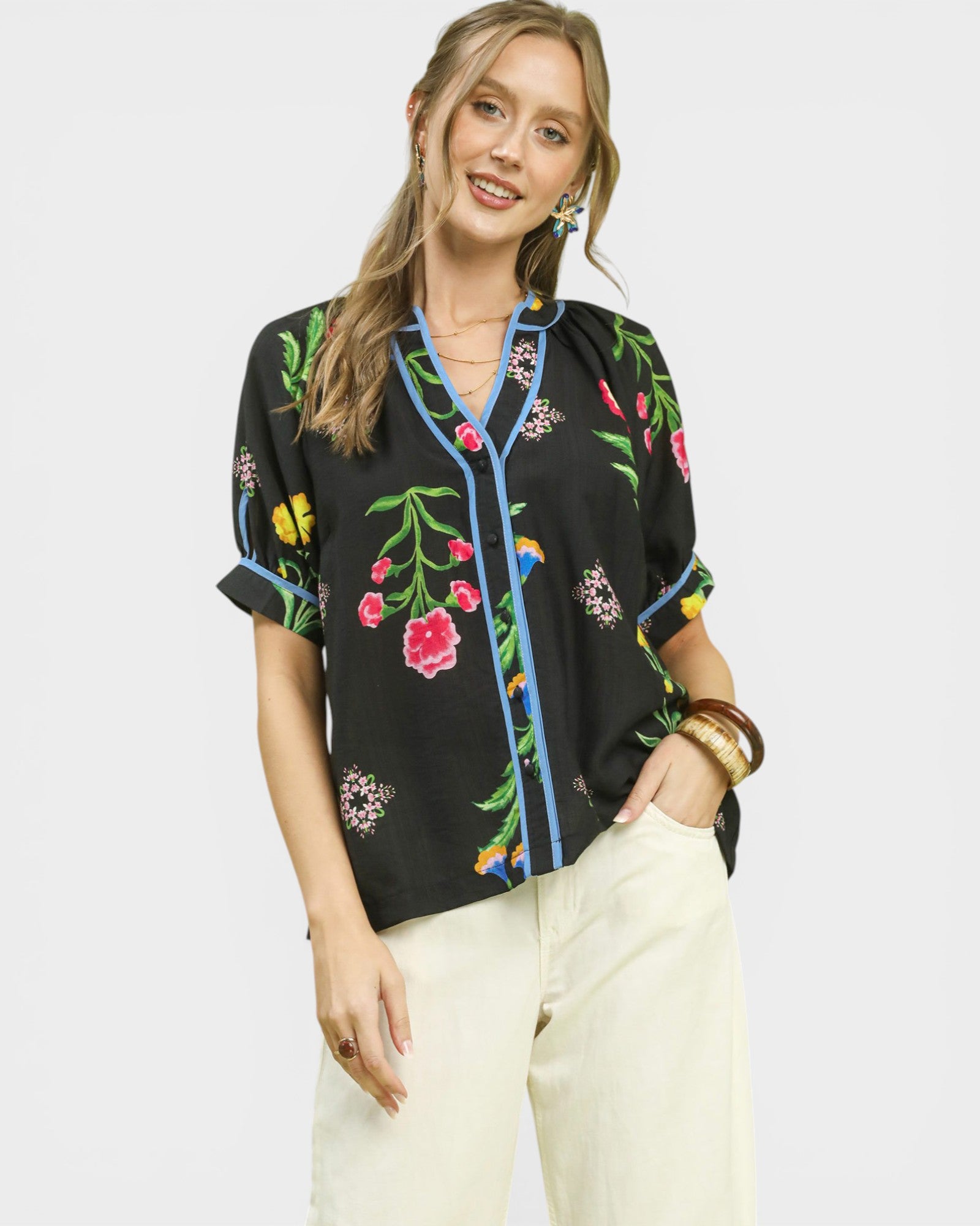 Woman wearing a black blouse with colorful floral embroidery on a white background