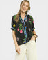 Woman wearing a black blouse with colorful floral embroidery on a white background