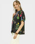 Woman wearing a black embroidered jacket with colorful floral patterns on a white background