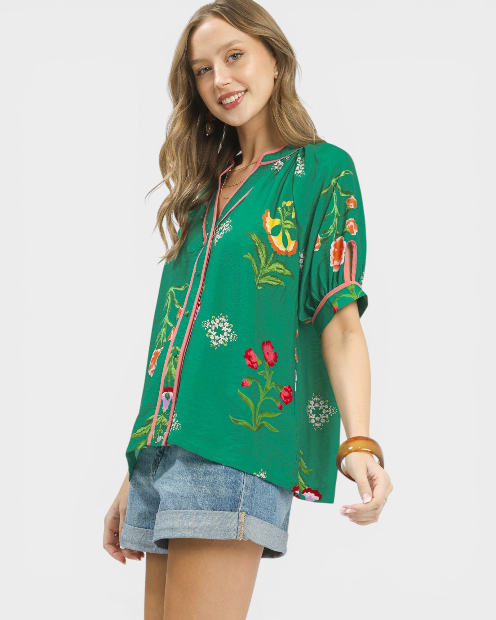 Woman wearing a green embroidered blouse with floral patterns on a white background