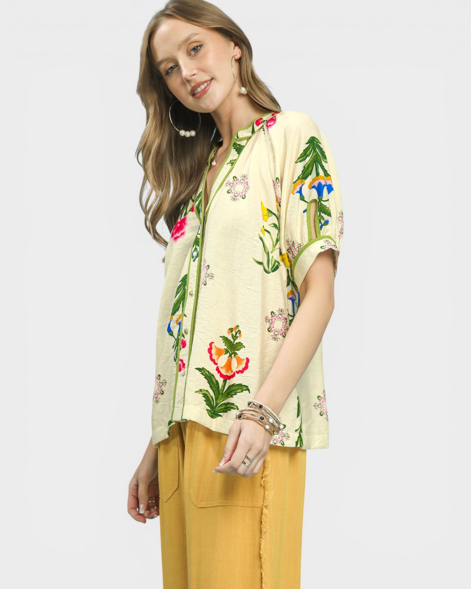 Woman wearing a floral embroidered blouse with yellow pants on a white background