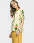 Woman wearing a floral embroidered blouse with yellow pants on a white background