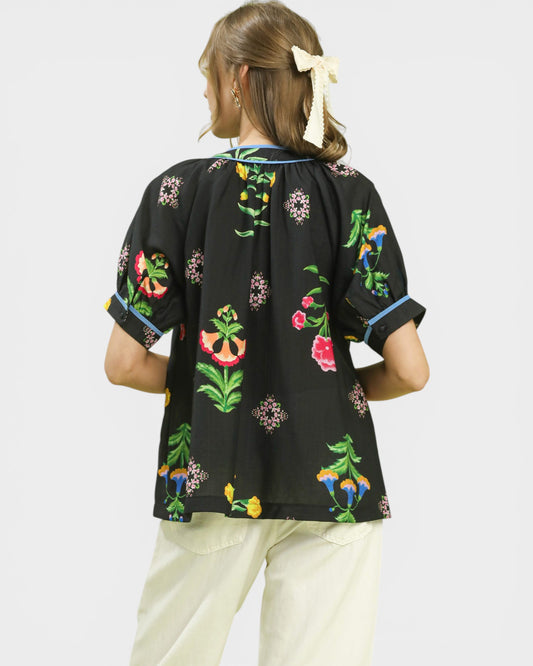 Woman wearing a black blouse with colorful floral embroidery on a white background