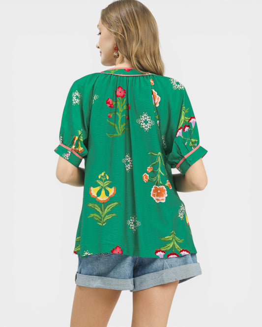 Green floral embroidered top worn by a person on a white background