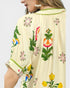 Cream-colored garment with colorful floral patterns on a plain background