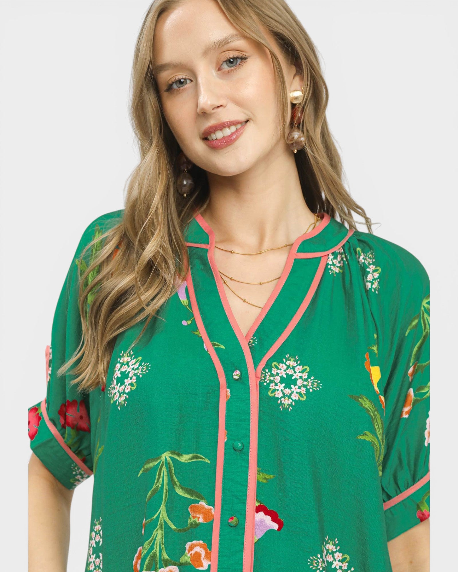 Woman wearing a green floral embroidered top on a white background
