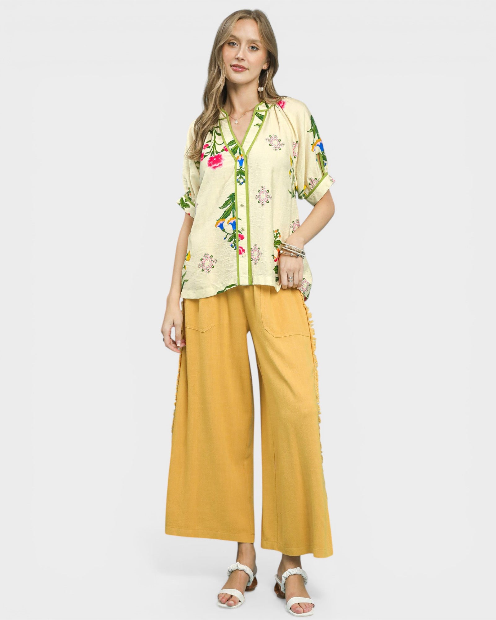 Woman wearing a floral blouse and yellow pants on a white background