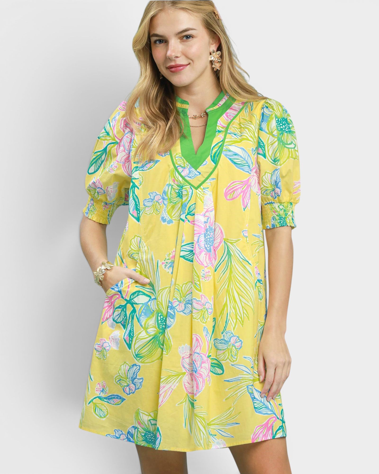 Woman wearing a yellow floral dress against a white background