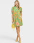 Woman wearing a green floral dress holding a yellow bag on a white background