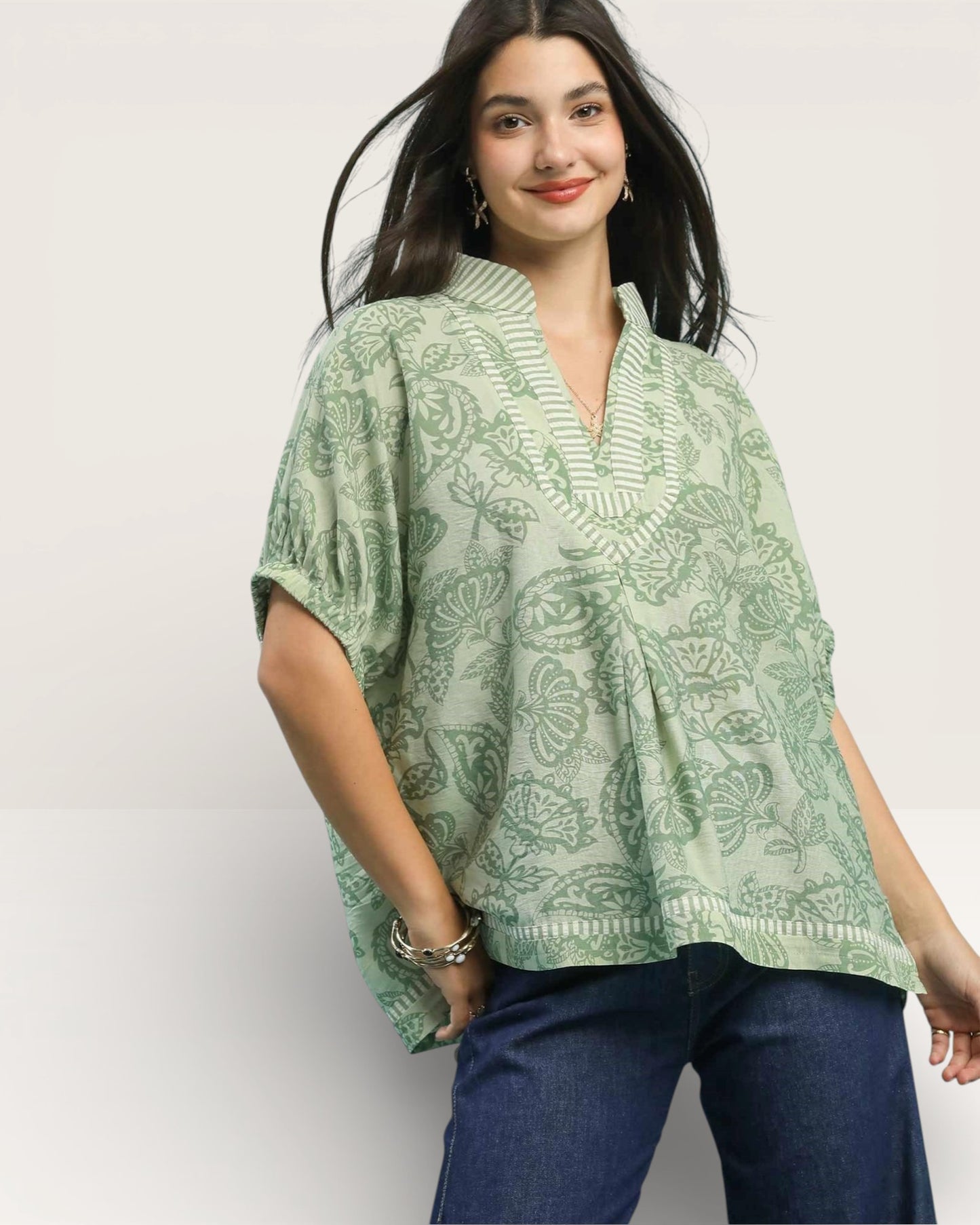 Woman wearing a green patterned top against a white background